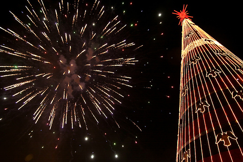 Yellow fireworks in the shape sphere on the right side on a Christmas Tree background.