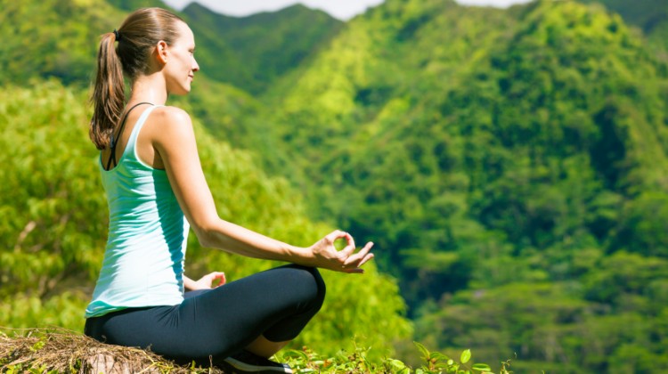 Woman meditating in beautiful outdoor setting.